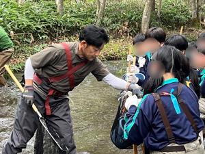 ウチダザリガニク駆除で学生に川の生物を見せて説明する学芸員