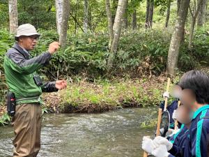 ウチダザリガニク駆除で学生に川の生態系について説明する学芸員